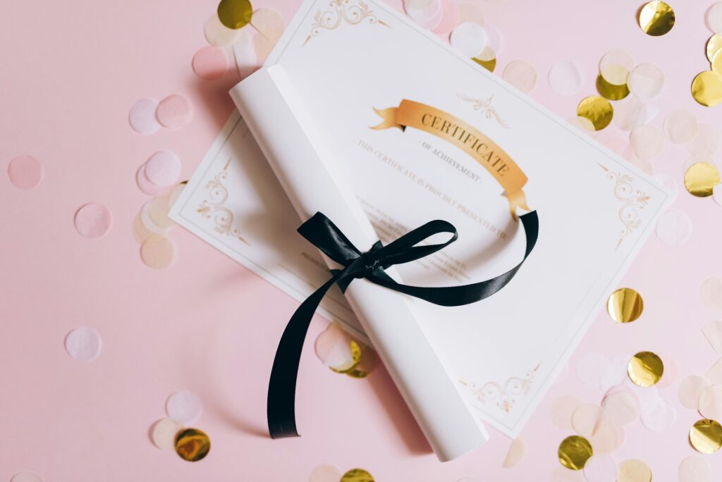 Professional certification award with black ribbon on pink background.