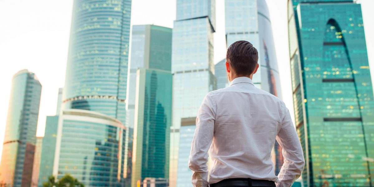 back-view-businessman-looking-copy-space-while-standing-against-glass-skyscraper-scaled.jpg